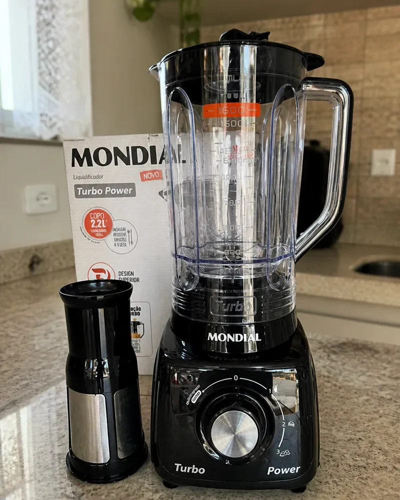 O Mondial L-99 FB preto numa bancada de granito claro, com o filtro de inox ao lado e a caixa atrás